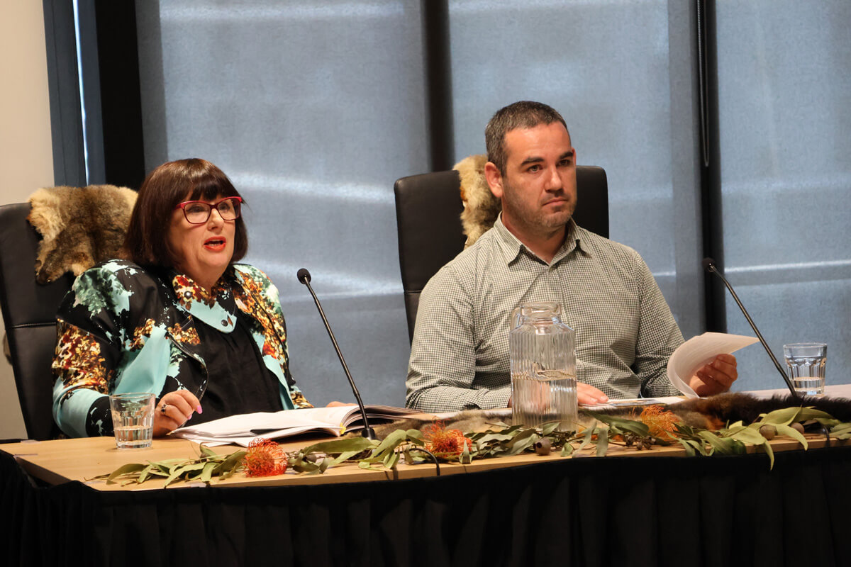 Magistrate Kay Macpherson and Ashley Morris sitting side by side at a table and presenting evidence at a Yoorrook public hearing
